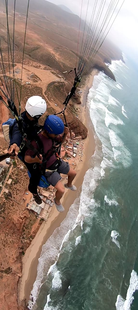 Vol en parapente biplace au-dessus de la plage et des falaises rouges