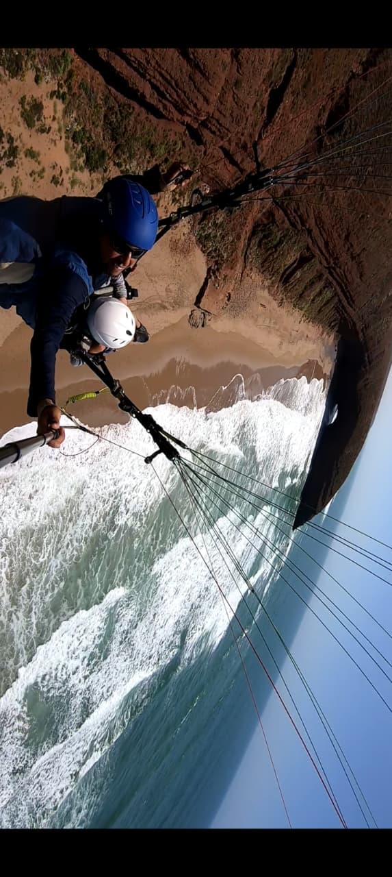 Vue plongeante sur la falaise et les vagues pendant un vol en parapente
