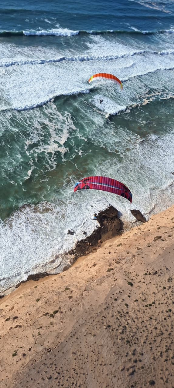 Parapentes au-dessus des falaises et des vagues de la côte d'Aglou