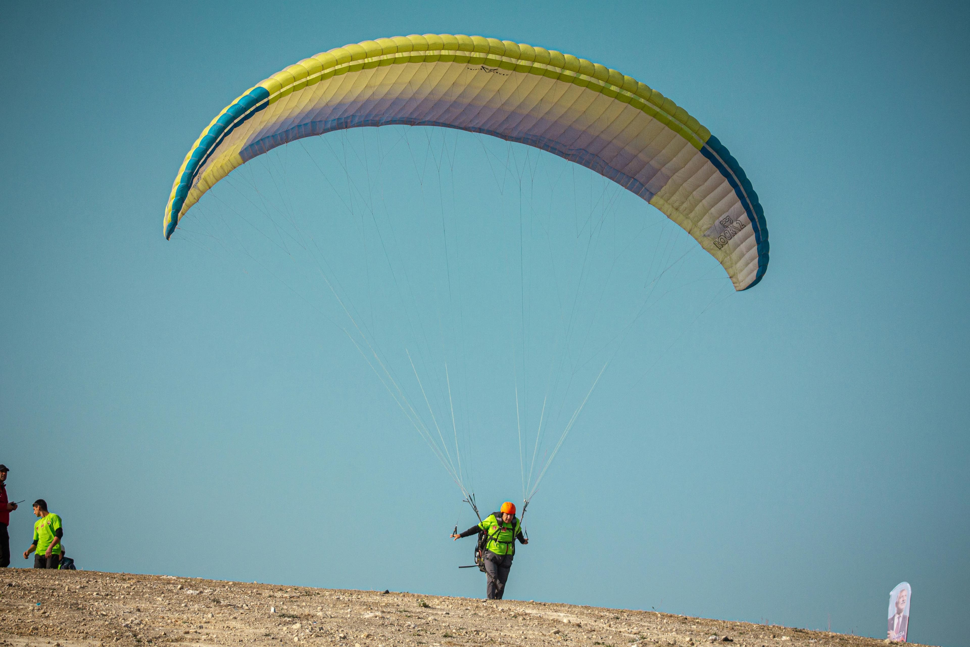 Pilote de parapente au décollage sur une dune face à l'océan